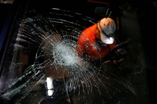 A man stands in a garage and next to a car with a shattered window after opposition supporters and security forces clashed in and outside the building on Tuesday according to residents, in Caracas, Venezuela June 14, 2017. REUTERS/Ivan Alvarado