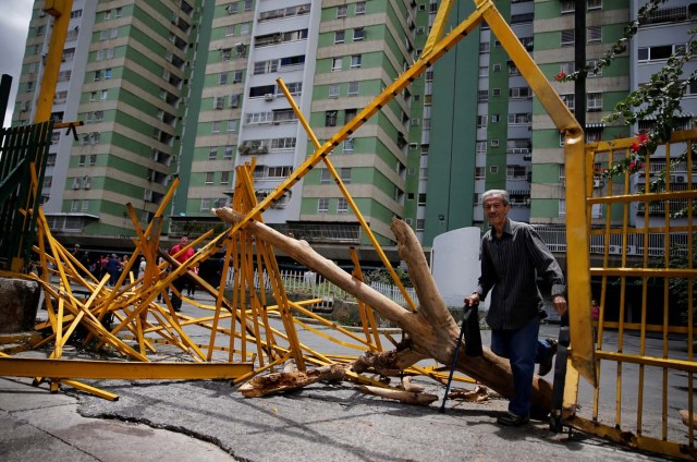 A man walks through a broken main gate after opposition supporters and security forces clashed in and outside residential buildings on Tuesday according to residents, in Caracas, Venezuela June 14, 2017. REUTERS/Ivan Alvarado TPX IMAGES OF THE DAY