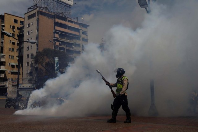 A riot police officer walks near tear gas during a rally against Venezuela's President Nicolas Maduro's government in Caracas, Venezuela June 14, 2017. REUTERS/Carlos Garcia Rawlins