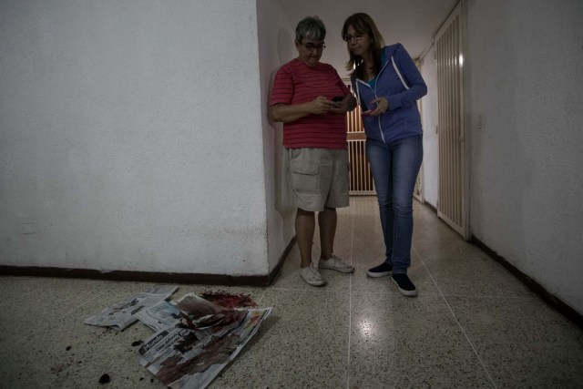 CAR01. CARACAS (VENEZUELA), 14/06/2017.- Yasmin Navarro (c) muestra la sangre de su perro Cros, al que le dispararon en las residencias Los Verdes ubicadas en el oeste de Caracas (Venezuela) hoy, miércoles 14 de junio de 2017. El oeste de Caracas fue sacudido anoche por la policía militarizada en un operativo que terminó, según el Gobierno venezolano, con la detención de 23 "terroristas" mientras que opositores aseguran hoy que se trató de una acción "terrible" en la que funcionarios causaron destrozos materiales y dispararon a mascotas. EFE/Miguel Gutiérrez