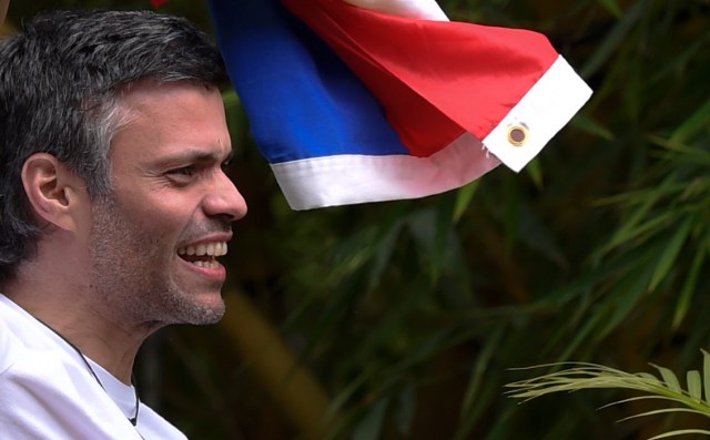 Venezuelan opposition leader Leopoldo Lopez displays a Venezuelan national flag as he greets supporters gathering outside his house in Caracas, after he was released from prison and placed under house arrest for health reasons, on July 8, 2017. Venezuela's Supreme Court confirmed on its Twitter account it had ordered Lopez to be moved to house arrest, calling it a "humanitarian measure" granted on July 7 by the court's president Maikel Moreno. "Leopoldo Lopez is at his home in Caracas with (wife) Lilian and his children," Lopez's Spanish lawyer Javier Cremades said in Madrid. "He is not yet free but under house arrest. He was released at dawn." / AFP PHOTO / Juan BARRETO