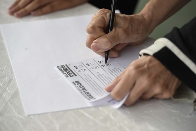 A woman marks her ballot on July 16, 2017 in Caracas, in an opposition-organized vote to measure public support for President Nicolas Maduro's plan to rewrite the constitution, against a backdrop of worsening political violence . The authorities have refused to greenlight a vote that has been presented as an act of civil disobedience and supporters of Maduro are boycotting it. So voters seemed set to reject the president's controversial plan. / AFP PHOTO / JUAN BARRETO