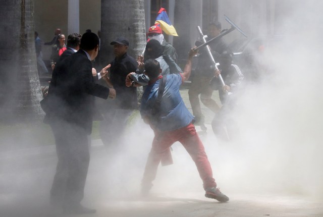Government supporters hold a national flag while clashing with people outside the National Assembly, in Caracas, Venezuela July 5, 2017. REUTERS/Carlos Garcia Rawlins