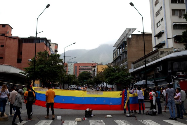 Opposition supporters build a barricade as they hold a Venezuelan national flag during a protest against Venezuela's President Nicolas Maduro in Caracas, Venezuela July 10, 2017. REUTERS/Marco Bello
