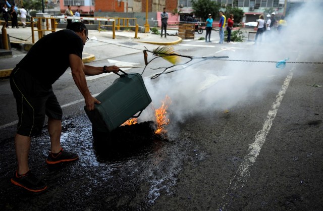 A man puts out a burning tire of a barricade during a protest against Venezuelan President Nicolas Maduro's government in Caracas, Venezuela July 10, 2017. REUTERS/Carlos Garcia Rawlins