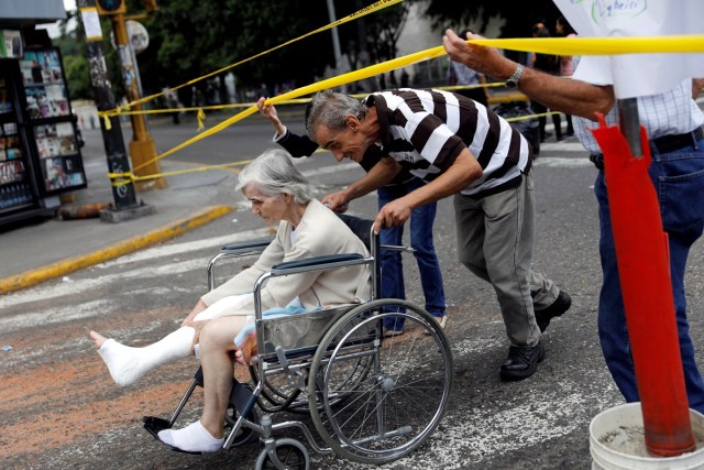 A man pushes a woman on a wheelchair as opposition supporters let them pass a road block during a protest against Venezuelan President Nicolas Maduro's government in Caracas, Venezuela July 10, 2017. REUTERS/Andres Martinez Casares