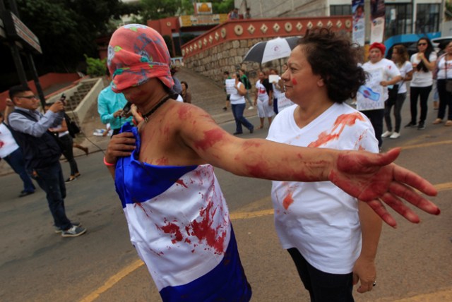 Members of a feminist group, one of them wrapped in a Honduras flag, take part in a protest against gender violence outside the presidential house in Tegucigalpa, Honduras, July 20, 2017. REUTERS/Jorge Cabrera