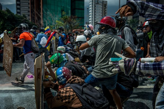 Manifestantes antigubernamentales lanzan piedras durante un enfrentamiento con fuerzas de seguridad en Caracas a principios de mayo. Credit Meridith Kohut para The New York Times