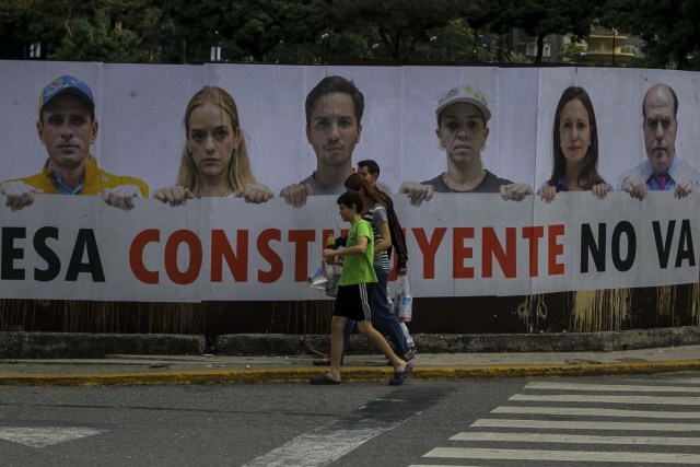 CAR13. CARACAS (VENEZUELA), 24/07/2017.- Transeúntes caminan frente a una valla en rechazo a la Asamblea Constituyente hoy, lunes 24 de julio de 2017, en un colegio electoral de Caracas (Venezuela). Venezuela inicia hoy la semana decisiva para la elección de la Asamblea Nacional Constituyente convocada por el presidente, Nicolás Maduro, con los oficialistas entrando en la recta final de su campaña en medio de protestas y llamados a paro de los opositores en rechazo a esos comicios. EFE/Miguel Gutiérrez