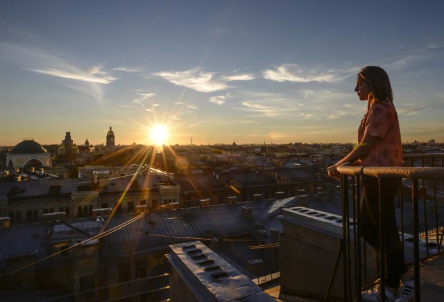 A tourist looks at the city during a visit to the first official tour of the roofs in St. Petersburg on August 11, 2017. / AFP PHOTO / OLGA MALTSEVA