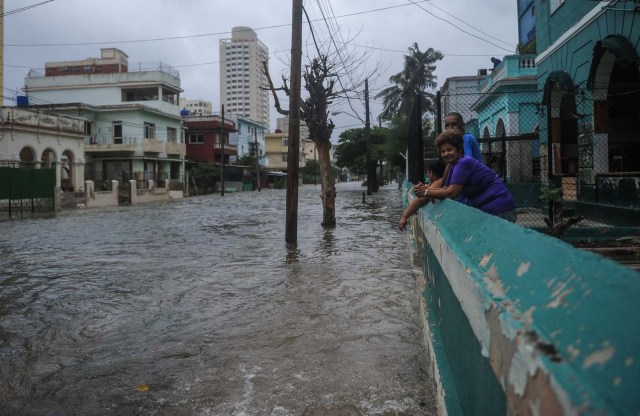 Locals watch flooded streets following the passage of Hurricane Irma in Havana, on September 9, 2017. Irma's blast through the Cuban coastline weakened it to a Category Three, but it is still packing winds of 125 miles (200 kilometer) per hour. / AFP PHOTO / YAMIL LAGE