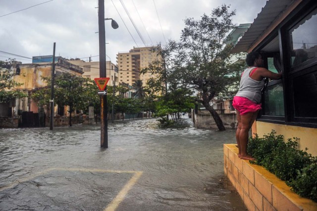 A woman shuts a window during the passage of Hurricane Irma in Havana, on September 9, 2017. Irma's blast through the Cuban coastline weakened it to a Category Three, but it is still packing winds of 125 miles (200 kilometer) per hour. / AFP PHOTO / YAMIL LAGE