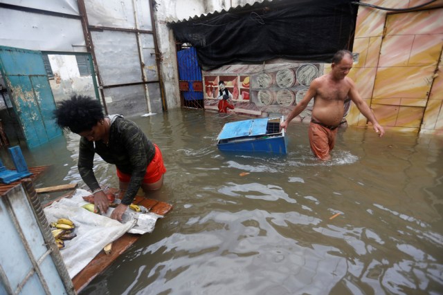 A woman rolls produce into a bag as a man drags a cooler through the water, after the passing of Hurricane Irma, in Havana, Cuba September 10, 2017. REUTERS/Stringer NO SALES. NO ARCHIVES