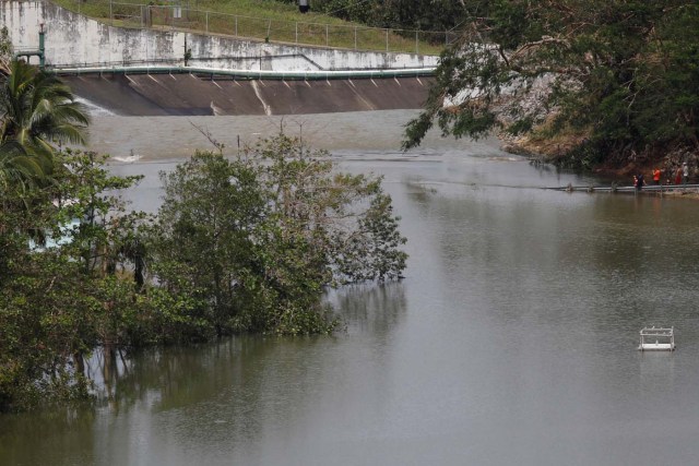 People look at water flowing over the road at the dam of the Guajataca lake after the area was hit by Hurricane Maria in Guajataca, Puerto Rico September 23, 2017. REUTERS/Carlos Garcia Rawlins