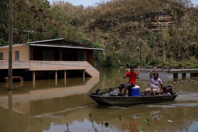 Local residents use a boat to pass next to a flooded houses close to the dam of the Guajataca lake after the area was hit by Hurricane Maria in Guajataca, Puerto Rico September 23, 2017. REUTERS/Carlos Garcia Rawlins