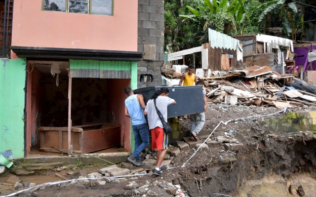 Men carry a refrigerator at a residential area affected by a landslide due to heavy rains caused by Tropical Storm Nate in Los Anonos neighbourhood, San Jose, on October 6, 2017. A national emergency alert was declared in Costa Rica, where eight people died, including a three-year-old girl, after they were hit by falling trees and mudslides. An alert was issued for people to be wary of crocodiles that might be roaming after rivers and estuaries flooded. / AFP PHOTO / Ezequiel BECERRA