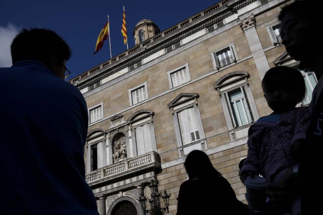 People walk past the Generalitat Palace in Barcelona on October 10, 2017. Spain's worst political crisis in a generation will come to a head as Catalonia's leader could declare independence from Madrid in a move likely to send shockwaves through Europe. / AFP PHOTO / PAU BARRENA