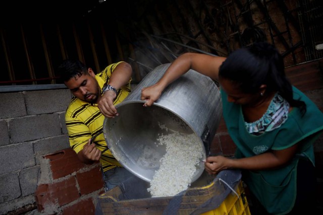 Medical equipment repairman Leandro Colmenares (L) makes corn dough at the backyard of his house in Caracas, Venezuela October 3, 2017. Picture taken October 3, 2017. REUTERS/Carlos Garcia Rawlins