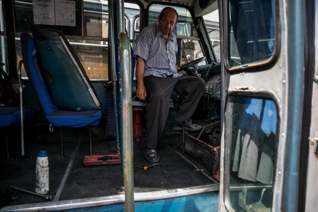 Fotografías del 10 de octubre del 2017, del conductor de un bus de transporte público, mientras espera por un mecánico, en la ciudad de Caracas (Venezuela). Los altos costos de mantenimiento, la disminución de importación de repuestos, una galopante inflación y la escasez de efectivo tienen al sistema de transporte de Venezuela en jaque, mientras la población padece los efectos de esta crisis con un pasaje inestable y largos tiempos de espera para trasladarse. EFE/MIGUEL GUTIÉRREZ