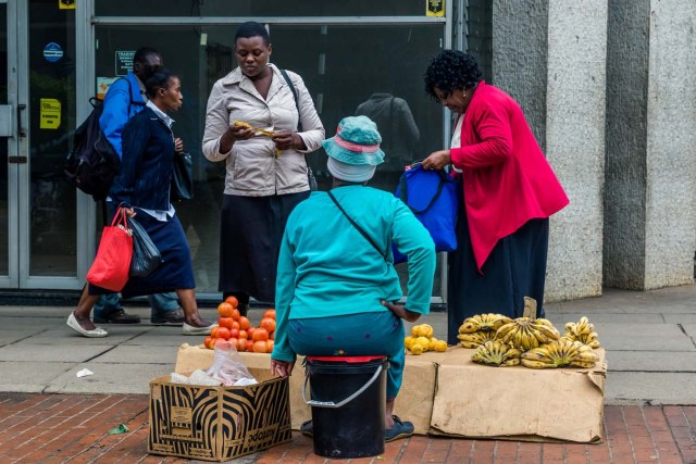 Residents buy fruits from a street vendor in Harare on November 15, 2017. Zimbabwe's military appeared to be in control of the country on November 15 as generals denied staging a coup but used state television to vow to target "criminals" close to President Mugabe. / AFP PHOTO / -