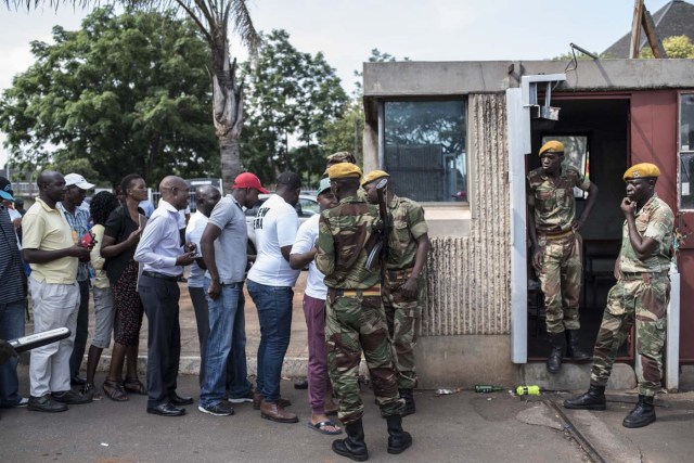 Soldiers check the supporters who arrive to welcome Zimbabwe's ousted vice president Emmerson Mnangagwa, at the entrance of the headquarters of Zimbabwe's African National Union Patriotic Front (ZANU PF) party in Harare, on November 22, 2017. / AFP PHOTO / STEFAN HEUNIS