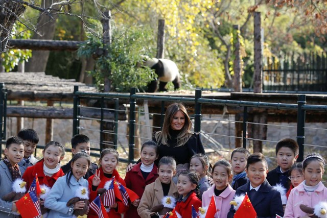 U.S. first lady Melania Trump poses for photos with children in front of a panda section as she visits Beijing Zoo in Beijing, China, November 10, 2017. REUTERS/Thomas Peter