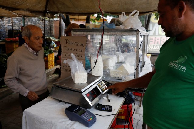 Un vendedor pesa queso para un cliente en un mercado callejero en Caracas, Venezuela, el 19 de diciembre de 2017. Foto tomada el 19 de diciembre de 2017. REUTERS / Marco Bello