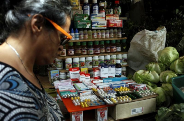 Una mujer pasa delante de un puesto de vegetales y frutas que además vende medicinas en un mercado en Rubio, Venezuela. Foto tomada el 5 de diciembre del 2017. REUTERS/Carlos Eduardo Ramirez