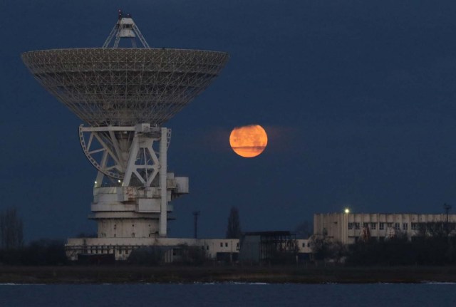 A "supermoon" full moon sets over the RT-70 radio telescope in the village of Molochnoye, Crimea January 2, 2018. REUTERS/Pavel Rebrov