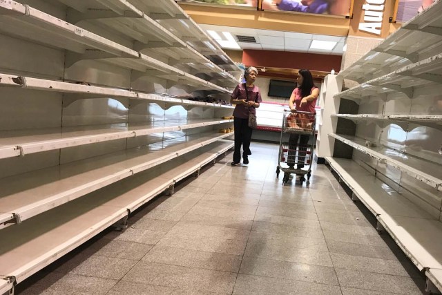 People walk past empty shelves at a supermarket in Caracas, Venezuela January 9, 2018. REUTERS/Marco Bello