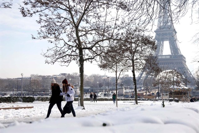 People walk on the snow-covered Trocadero gardens near the Eiffel Tower in Paris, as winter weather with snow and freezing temperatures arrive in France, February 8, 2018. REUTERS/Charles Platiau