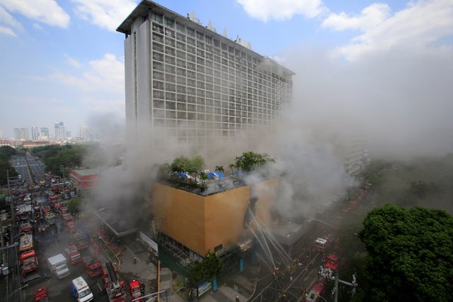 Los bomberos empapan agua después de que un incendio envolvió el hotel Manila Pavilion en Metro Manila, Filipinas el 18 de marzo de 2018. REUTERS / Romeo Ranoco