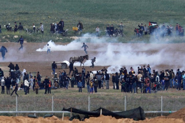 Los palestinos huyen del gas lacrimógeno en el lado de Gaza de la frontera entre Israel y Gaza, visto desde el lado israelí de la frontera, el 30 de marzo de 2018. REUTERS / Amir Cohen 