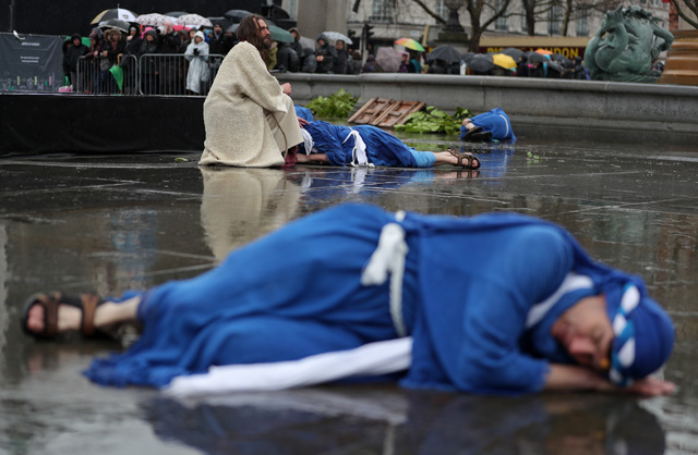 Actor James Burke-Dunsmore (C) plays the role of Jesus Christ, during a performance of Wintershall's 'The Passion of Jesus' on Good Friday in Trafalgar Square in London on March 30, 2018.  The Passion of Jesus tells the story from the Bible of Jesus's visit to Jerusalem and his crucifixion. On Good Friday 20,000 people gather to watch the Easter story in central London. One hundred Wintershall players bring their portrayal of the final days of Jesus to this iconic location in the capital. / AFP PHOTO / Daniel LEAL-OLIVAS