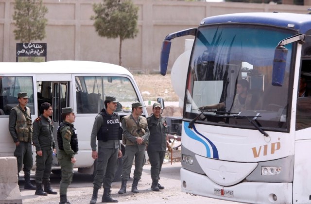 Soldados del Ejército sirio aparecen de pie junto a autobuses que transportan a los rebeldes y sus familias que salieron desde Duma, a la entrada del campo Wafideen en Damasco, Siria. 12 de abril, 2018. REUTERS/Omar Sanadiki