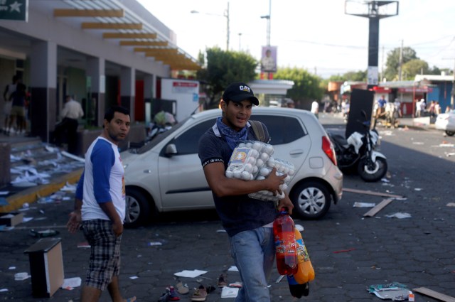A man with goods looted from a store walks along a street after protests over a controversial reform to the pension plans of the Nicaraguan Social Security Institute (INSS) in Managua, Nicaragua April 22, 2018. REUTERS/Jorge Cabrera