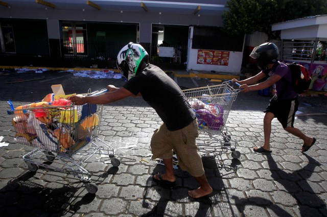 People with goods looted from a store walk pushing a shopping trolleys along a street after protests over a reform to the pension plans of the Nicaraguan Social Security Institute (INSS) in Managua, Nicaragua April 22, 2018. REUTERS/Jorge Cabrera