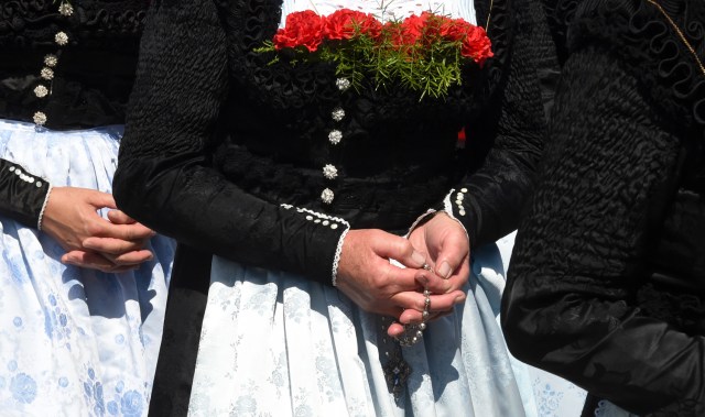 Una mujer con un traje típico bávaro sostiene un rosario mientras participa en la tradicional procesión de Corpus Christi cerca de la pequeña aldea bávara de Wackersberg, en el sur de Alemania, el 31 de mayo de 2018. / AFP PHOTO / Christof STACHE