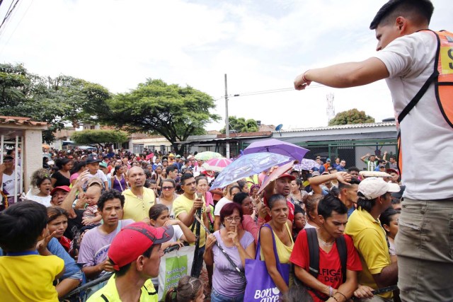 CUC01. CÚCUTA (COLOMBIA), 04/05/2018.- Fotografía del 3 de mayo de 2018, de un grupo de venezolanos mientras reciben asistencia alimentaria en Cúcuta (Colombia). Bajo el sol intenso de la ciudad colombiana de Cúcuta, cientos de familias venezolanas que huyeron de su país por la crisis económica y política hacen fila para reclamar los bonos alimentarios que entrega el Programa Mundial de Alimentos (PMA) de la ONU en las zonas de frontera. El proyecto que comenzó este lunes en Cúcuta, capital de Norte de Santander, surge como la primera gran respuesta de la comunidad internacional al delicado estado alimentario del 90 % de los cerca de 35.000 venezolanos que cruzan a diario las fronteras con Colombia en busca de oportunidades. EFE/SCHNEYDER MENDOZA